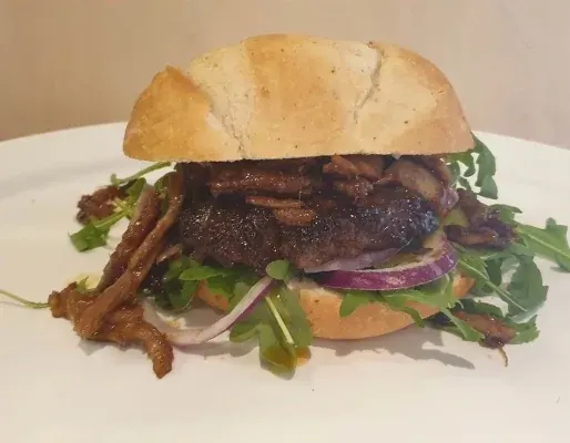 Hamburger met rucola, rode ui en gesmolten kaas